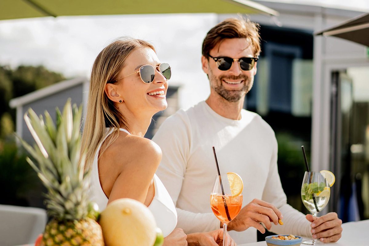 Ein Paar steht an der Rooftop Bar Tschadun PIZ mit einem Cocktail und einer Schale Nüssen